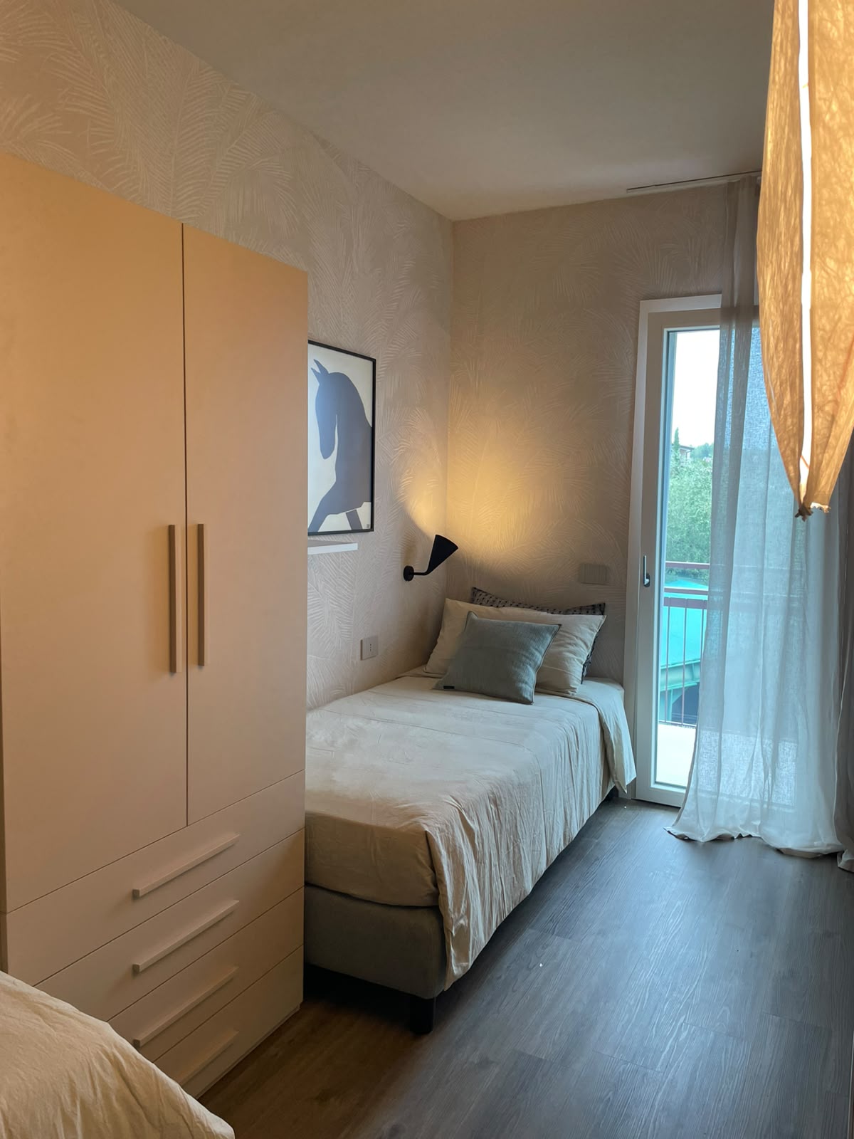 Schlafzimmer mit Einzelbett, Kleiderschrank und Terrassentür